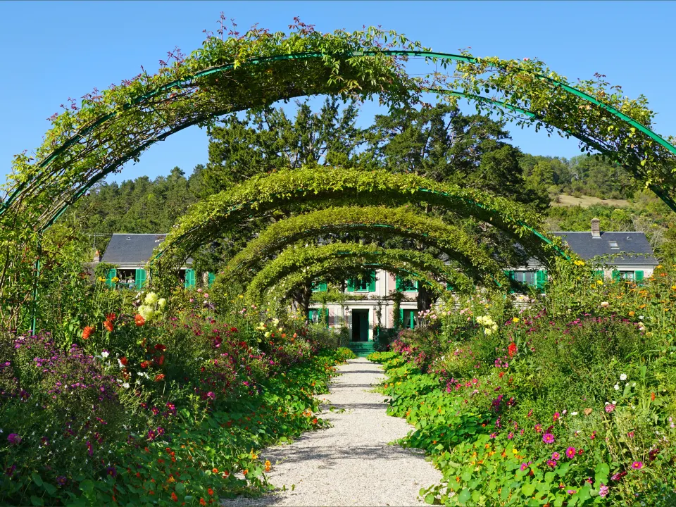 Tunnel de rosiers et de fleurs menant à la maison rose aux volets verts, à Giverny