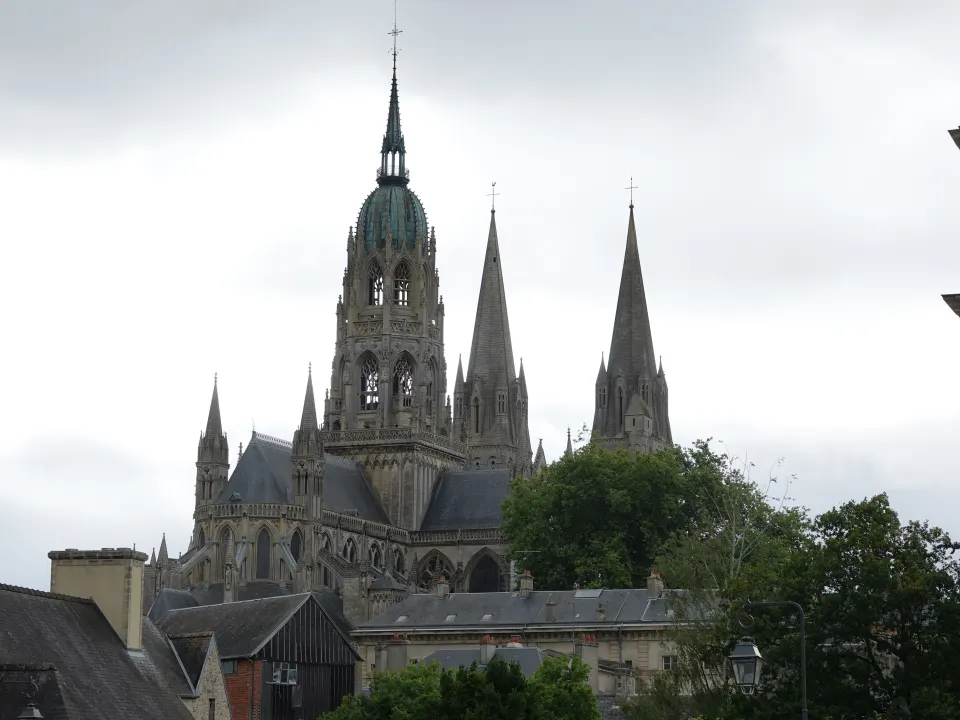 La cathédrale Notre-Dame de Bayeux et ses flèches de pierre sous un ciel gris clair
